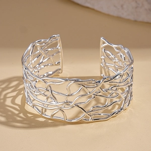 Close-up of silver open cuff bracelet with irregular woven hollow metal texture