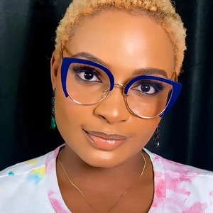 Close-up of cat-eye glasses with blue and gold frames worn by a model on black background