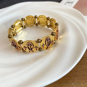 Detail of vintage elastic bracelet with hammered gold fish and cross religious symbols