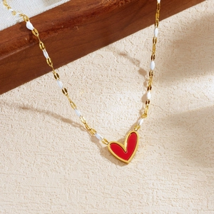 Fashionable gold-plated necklace with a red acrylic heart pendant and white enamel details