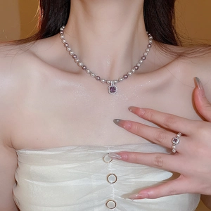 Detail of zircon manta rose pearl necklace with purple gemstone on female model