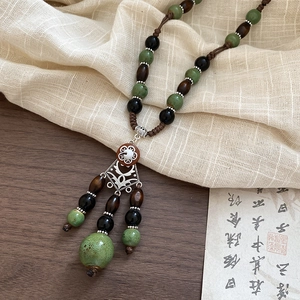 Detail of bohemian necklace with green ceramic beads and vintage hollow metal pendant