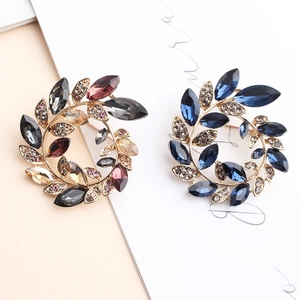 Elegant floral wreath brooches with colorful gemstones on a gold-plated metal base