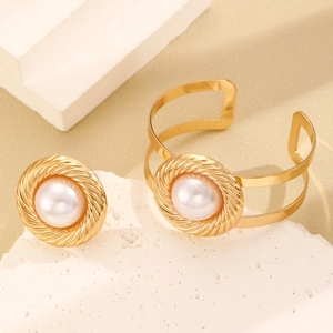Detalle del conjunto de anillo y brazalete dorados trenzados con perlas blancas