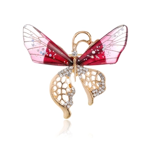 Detail van elegante gouden vlinderbroche met rode vleugels en kristallen accenten