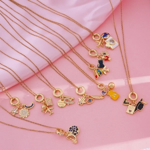 Gold-plated charm necklace with airplane and travel pendants on pink silk background