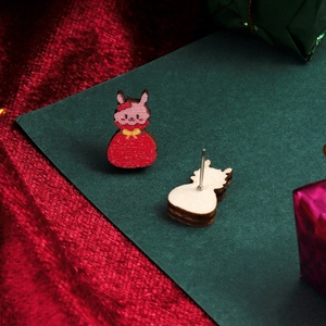 Detailed close-up of cute wooden bunny stud earrings with red and pink holiday patterns