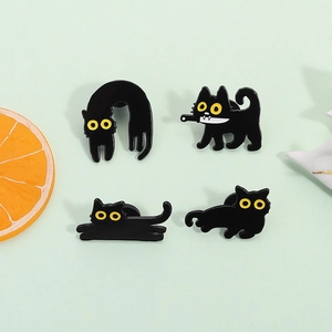 Set of four cute black cat enamel pins in various poses on light green background
