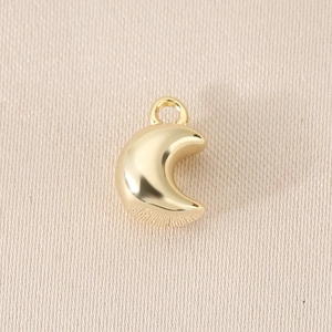Detail of a 14K gold plated crescent moon pendant with smooth metallic finish for DIY jewelry