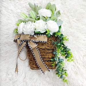 Detail of white peony flower basket with lamb ear leaves and a rustic burlap bow