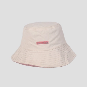 Detail showing beige bucket hat with pink embroidered logo and red checkered lining