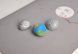 Detailed view of Earth and Moon planet pins on a dark notebook cover for accessories