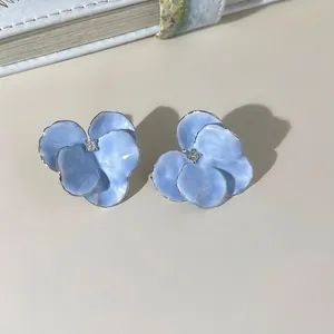 Macro detail of light blue floral earrings with silver plating and zircon center