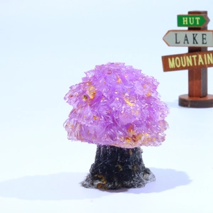 Detail of amethyst crystal tree with golden sparkles on a dark stone base decoration