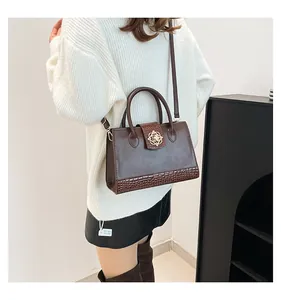 Detail of dark brown tote bag featuring crocodile pattern leather and golden floral buckle