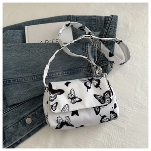 Detailed shot of white butterfly print crossbody bag with fabric texture and wide strap
