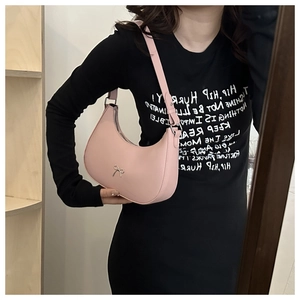 Detail of pink crescent bag featuring metallic bow ornament and smooth faux leather