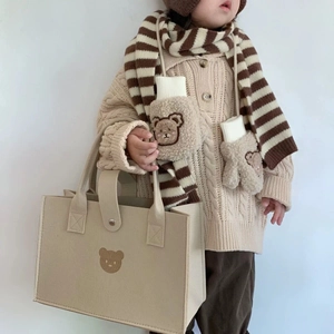 Close-up of children's knit set with striped scarf, bear gloves and beige felt bag
