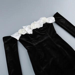 Close-up of off-shoulder neckline with three white silk roses on black velvet dress