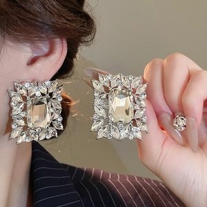 Close-up of square crystal earrings with leaf accents and silver metal base