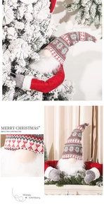 Close-up of knitted Christmas gnome topper with long arms wrapping around a tree