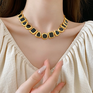 Close-up of vintage gold necklace with black enamel geometric stones on a model's neck