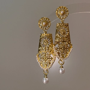 Close-up of vintage gold hollow geometric earrings with delicate pearl drop detail