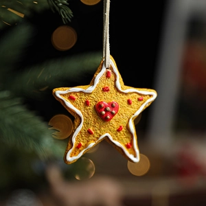 Gingerbread star resin Christmas ornament with red heart detail and festive bokeh background