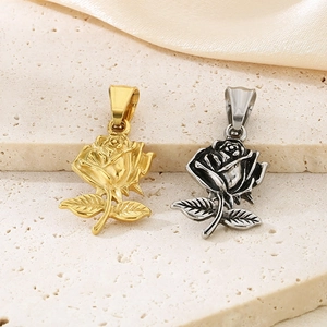 Pendentifs fleur de rose en acier titane doré et argenté sur surface en pierre