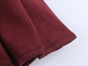 Gros plan détaillé sur le tissu en daim bordeaux et les finitions à double couture