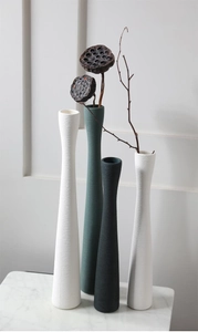 Dettaglio di quattro vasi sottili in ceramica con trama a spirale su marmo bianco
