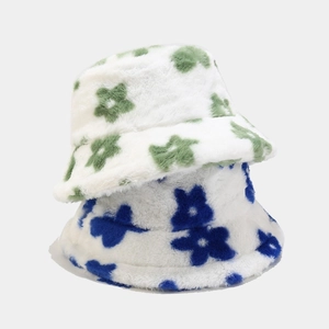 Close-up of thick plush bucket hats with green and blue floral patterns on white faux fur