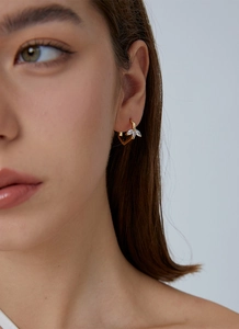 Close-up of elegant gold earrings with leaf-shaped marquise zircons on model ear