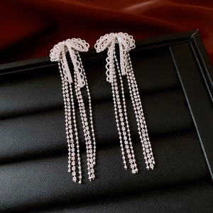 Detail of silver bow tassel earrings with sparkling zircons in a jewelry box