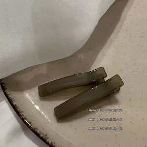 Detail of two dark grey hair clips on a ceramic tray for minimalist styling