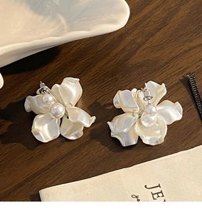 Dettaglio di orecchini a fiore con perle su uno sfondo di legno strutturato