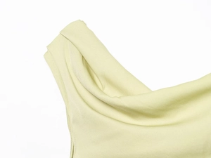 Detail of the elegant asymmetric off-shoulder pleats on light lime green fitted top