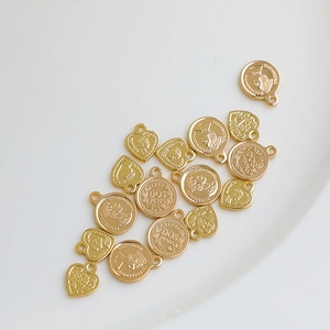 Detailansicht von 14K vergoldeten Herz- und Münzanhängern mit Königin-Relief-Design
