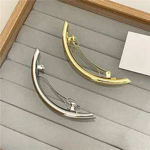 Close-up of elegant gold and silver metal hair clips displayed on a velvet jewelry tray