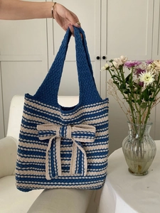 Detailed close-up of blue and white striped knit tote bag with large decorative bow