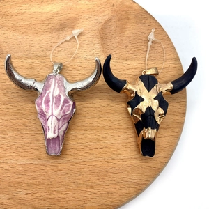 Detail view of colorful bull skull pendants with metallic frames on a wood tray