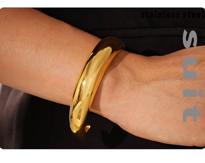 Close-up of a wide polished 18K gold plated stainless steel C-shaped cuff on a wrist