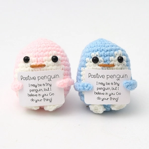 Close-up of pink and blue crochet positive penguins with encouraging message cards