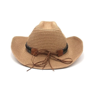 Détail d'un chapeau de paille de l'ouest avec bande ethnique et finitions en cuir marron