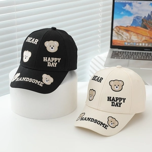 Detail of bear embroidery and Happy Day text on kids baseball caps in black and cream