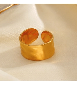 Detailed view of irregular hammer-patterned gold-plated ring on soft cream satin fabric