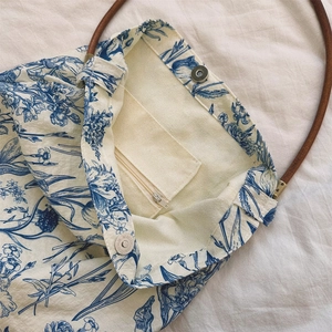 Detail of blue floral canvas tote bag featuring inner zipper pocket and magnetic snap closure