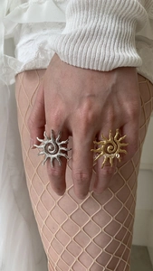 Detail of chunky gold and silver sunburst rings with spiral texture on a hand