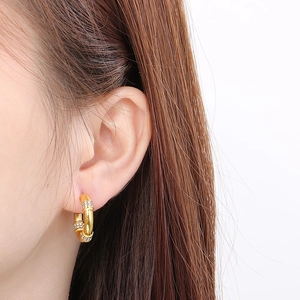 Gros plan de boucles d'oreilles créoles dorées style bambou serties de cristaux
