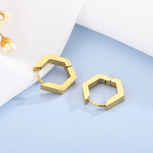 Gros plan détaillé des boucles d'oreilles hexagonales dorées sur fond minimaliste moderne